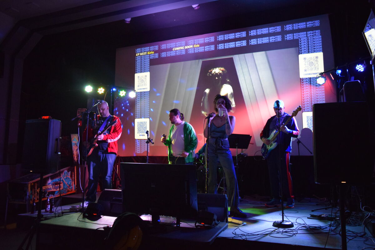 Full stage production with band, singer, projected music video, and stage lighting