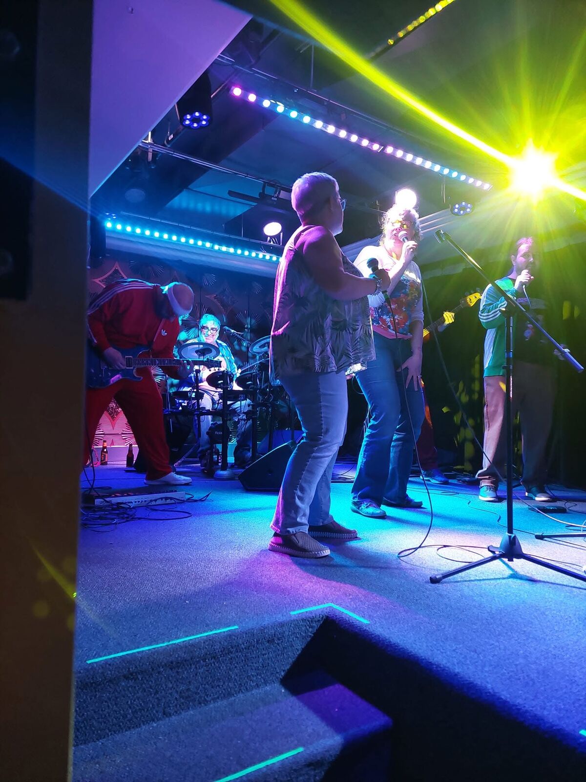 Two performers singing together on stage with the band